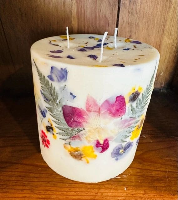 A candle with flowers on it sitting on top of a table.