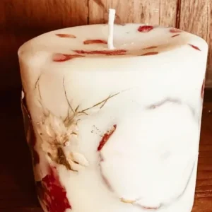 A candle with flowers on it sitting on top of a table.